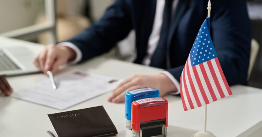 Founder reviewing L‑1A visa petition documents in the U.S. with passport and approval/rejection stamps visible.