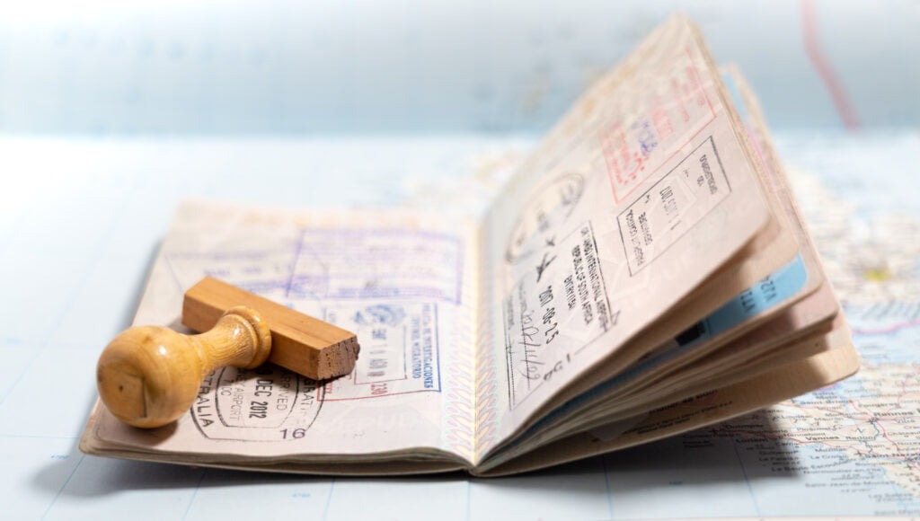 Open passport with visa stamps placed on a travel map