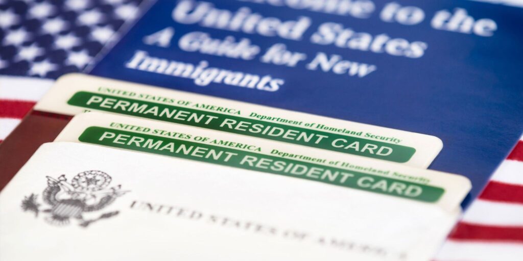 Permanent resident cards on a U.S. passport and American flag.