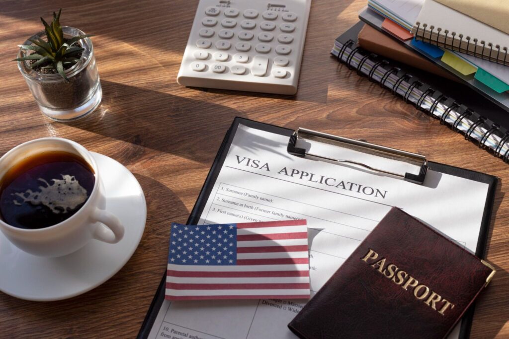 US visa application form, passport, and American flag on a desk