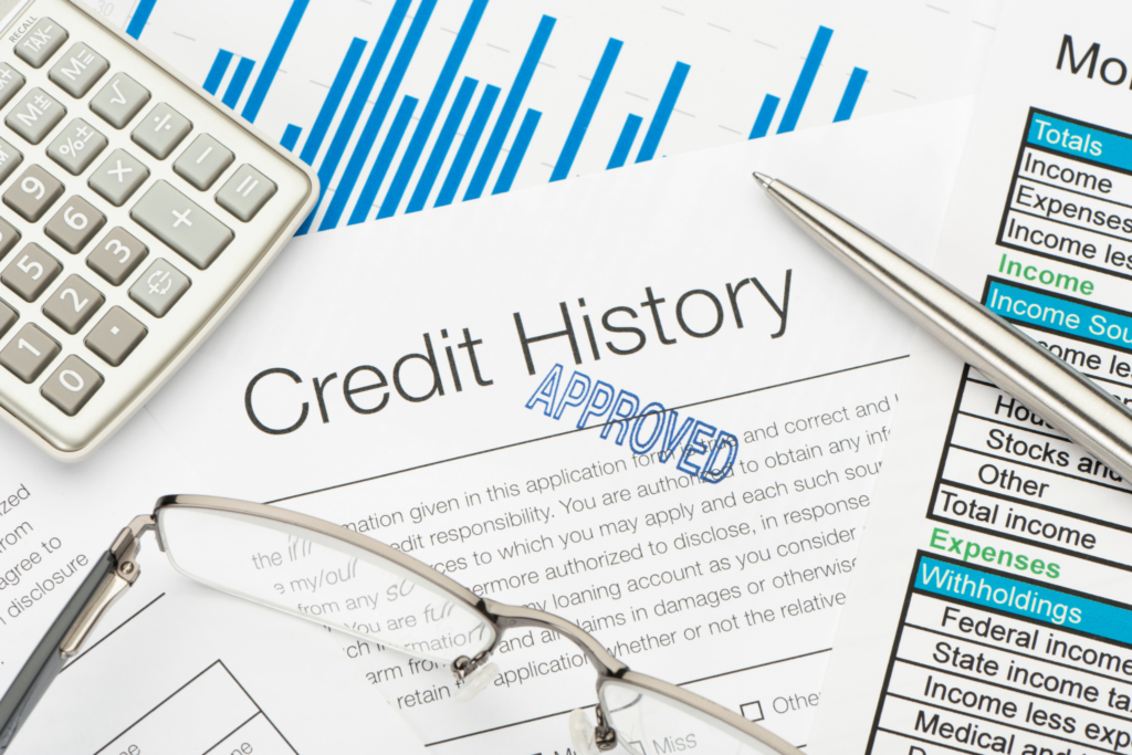 Approved US credit history document with calculator, glasses, pen, and income tax forms representing credit application review