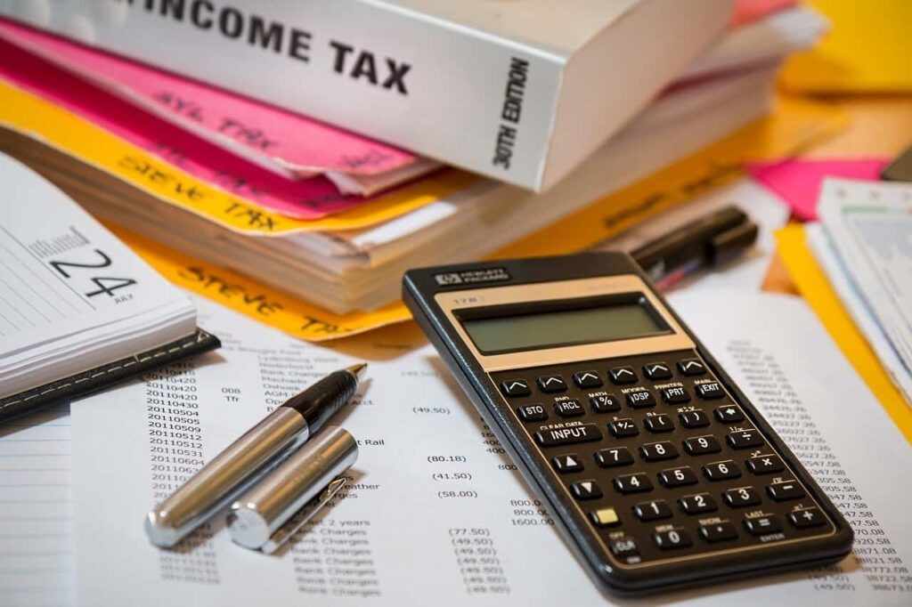 Calculator, pens, and tax documents on a desk representing professional tax preparation