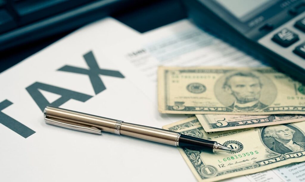Pen, US dollar bills, and tax documents symbolizing tax planning